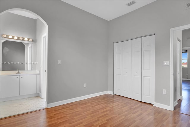 unfurnished bedroom with connected bathroom, sink, and light wood-type flooring