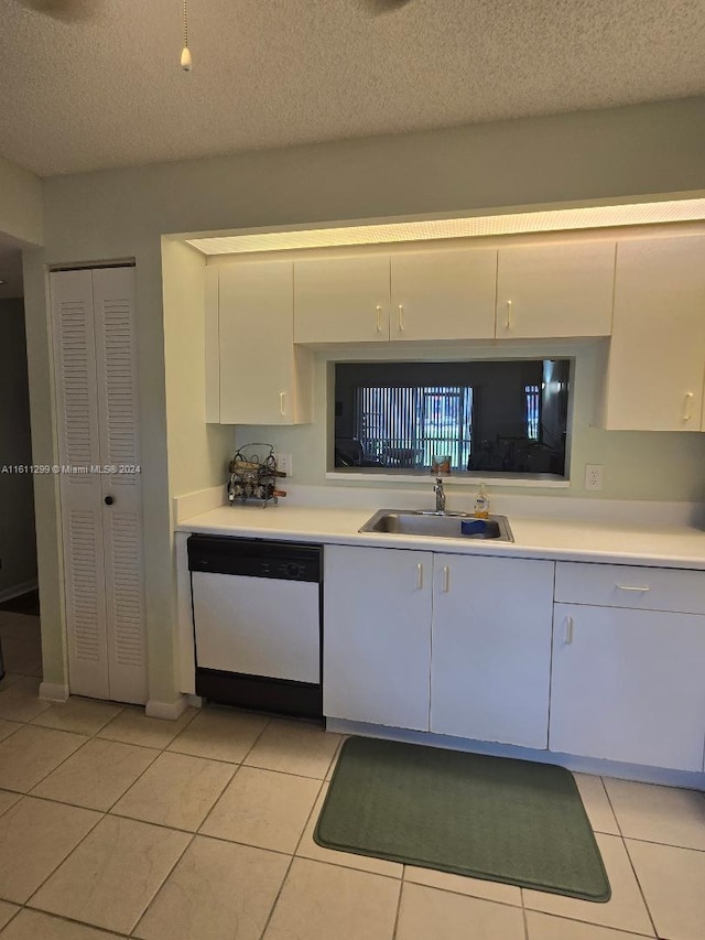 kitchen featuring dishwasher, white cabinets, sink, light tile patterned floors, and a textured ceiling