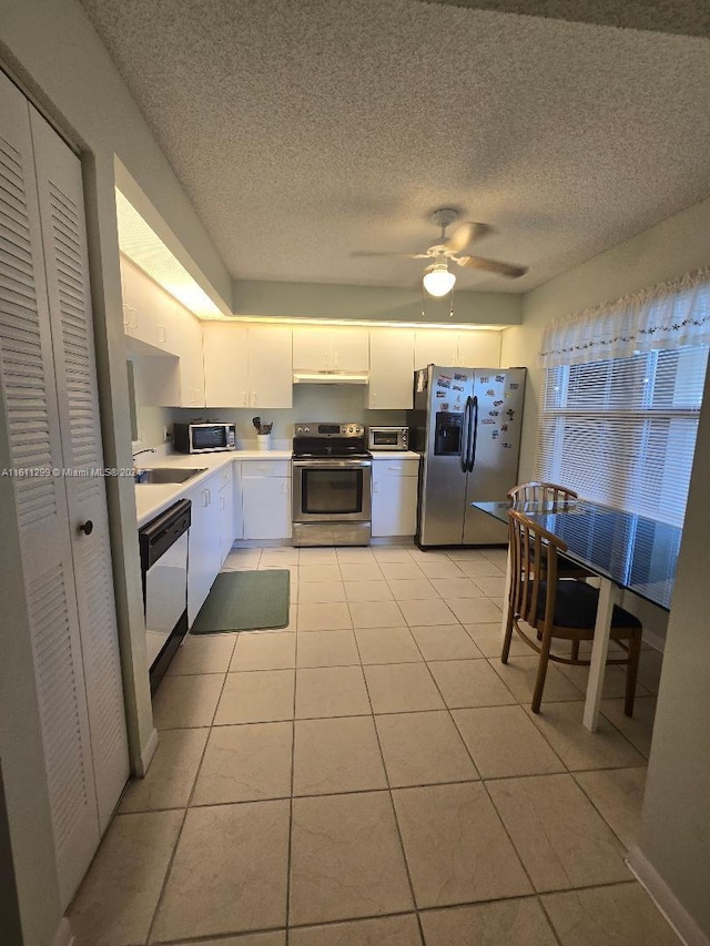 kitchen with sink, ceiling fan, light tile patterned floors, white cabinetry, and stainless steel appliances