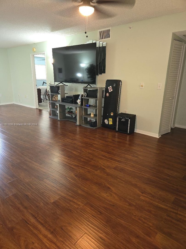 living room featuring ceiling fan, dark hardwood / wood-style floors, and a textured ceiling