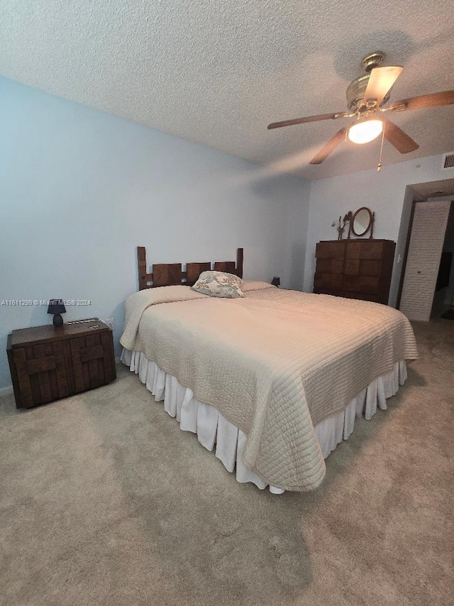 bedroom featuring light carpet, a textured ceiling, and ceiling fan