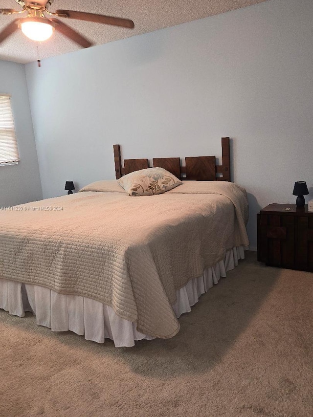 bedroom with ceiling fan, carpet, and a textured ceiling