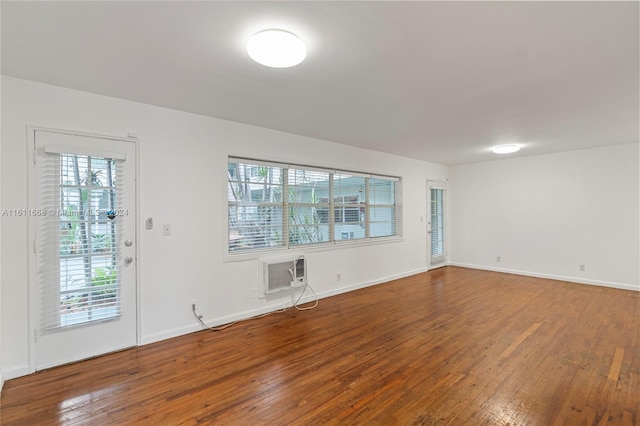 spare room featuring an AC wall unit and wood-type flooring