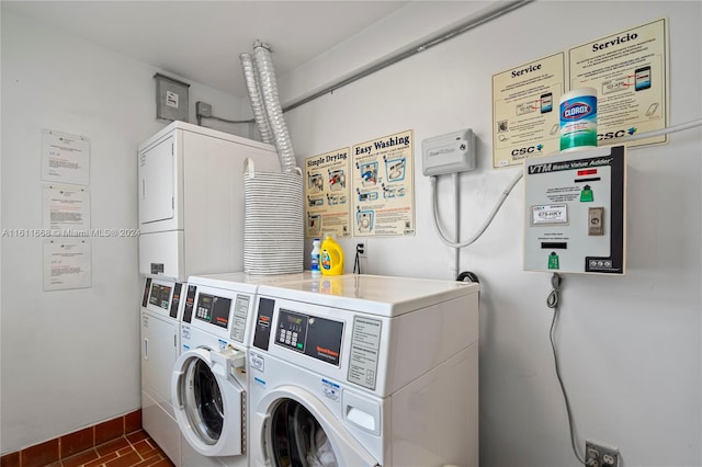 clothes washing area featuring stacked washer and clothes dryer, dark tile patterned floors, and washer and clothes dryer