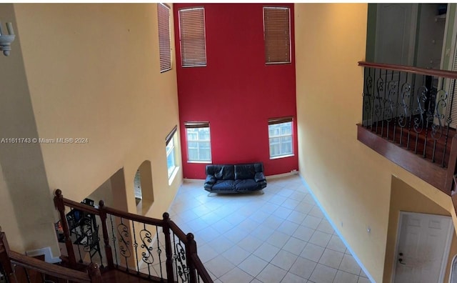 interior space featuring baseboards, stairway, a high ceiling, and tile patterned floors