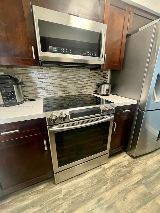 kitchen with light hardwood / wood-style flooring, stainless steel appliances, and tasteful backsplash