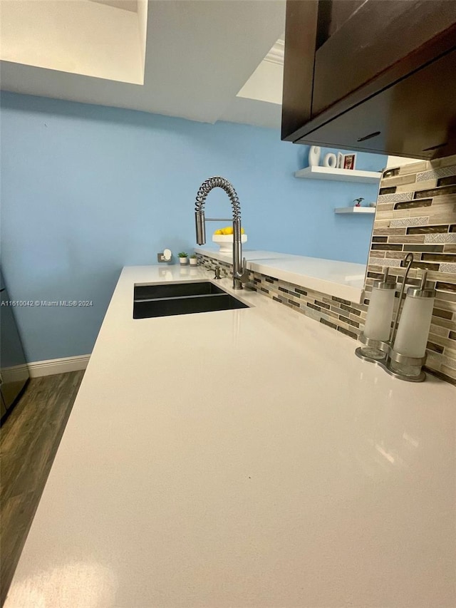 room details featuring sink, wood-type flooring, and tasteful backsplash