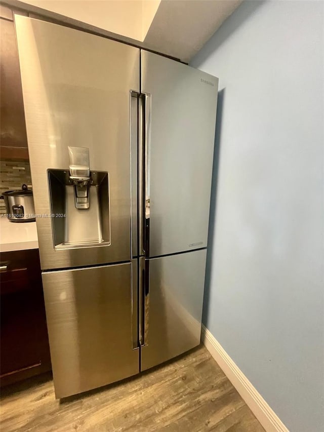 interior details with stainless steel fridge with ice dispenser and light wood-type flooring