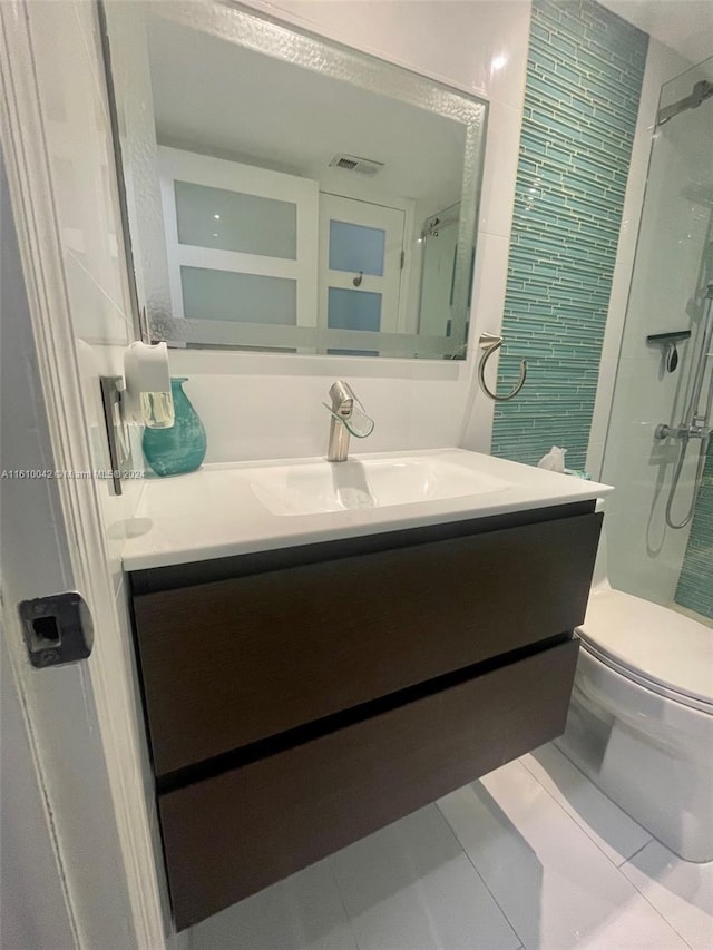 bathroom featuring toilet, vanity, tile patterned flooring, and a shower with door