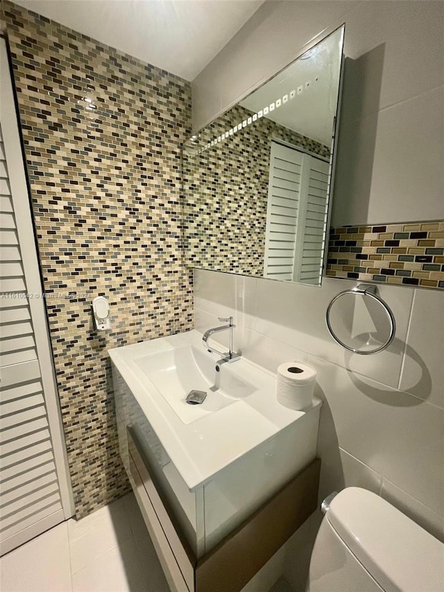 bathroom featuring tasteful backsplash, tile walls, toilet, and tile patterned flooring