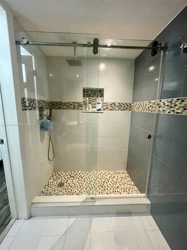 bathroom with a tile shower and tile patterned floors