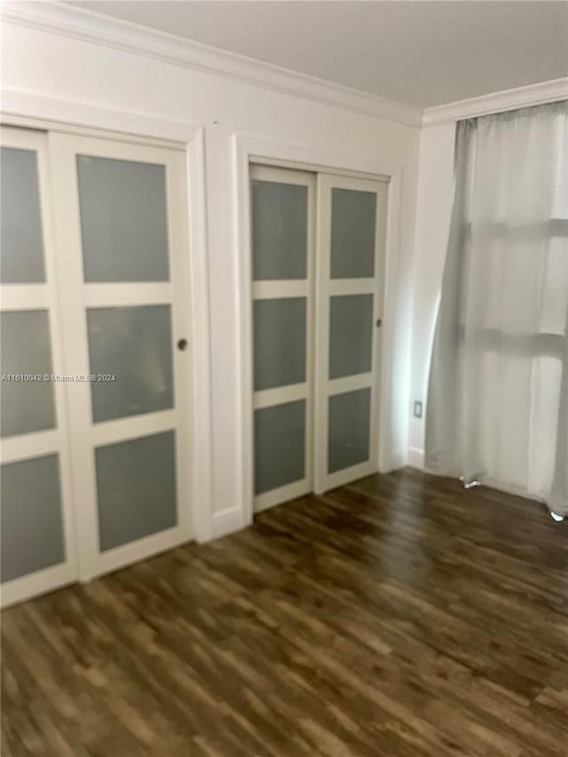 unfurnished room featuring ornamental molding and dark hardwood / wood-style flooring