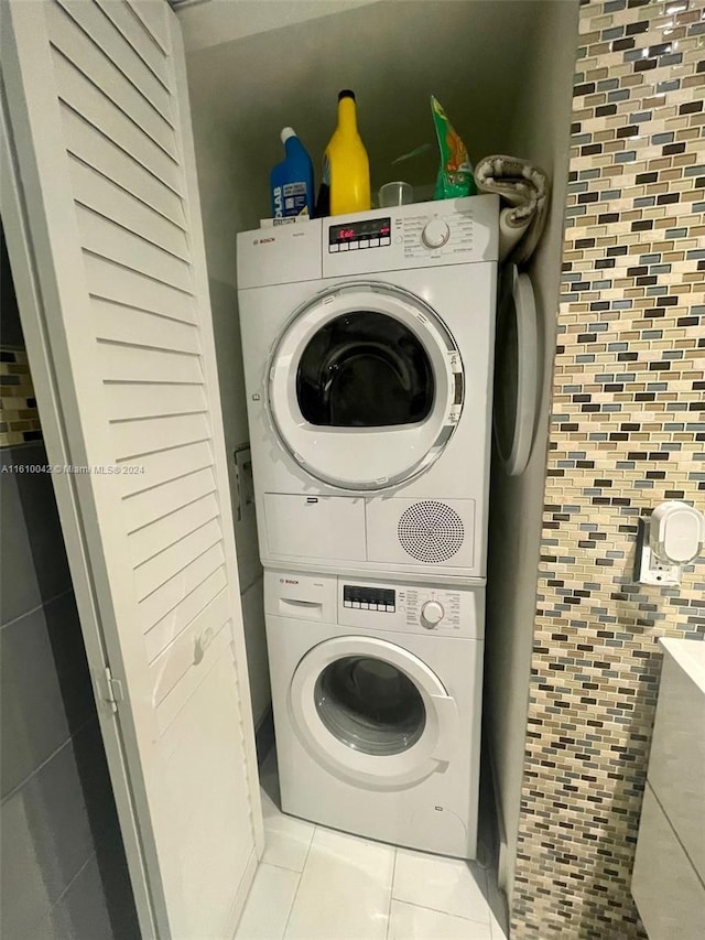 washroom with light tile patterned floors and stacked washer / drying machine