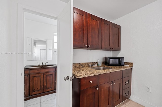 kitchen featuring sink, light stone countertops, and light tile floors