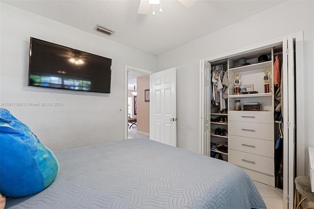 bedroom with a textured ceiling, a closet, ceiling fan, and light tile floors