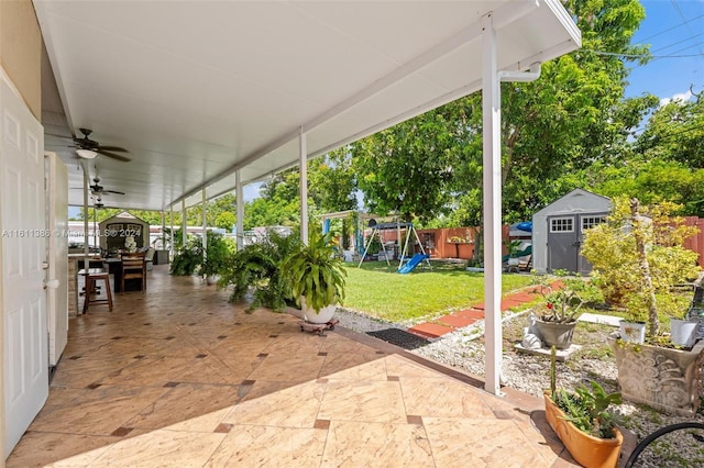 view of terrace with a playground, ceiling fan, and a storage unit