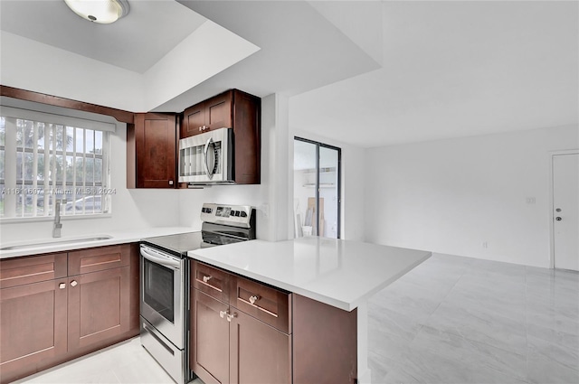 kitchen featuring dark brown cabinets, kitchen peninsula, sink, and appliances with stainless steel finishes