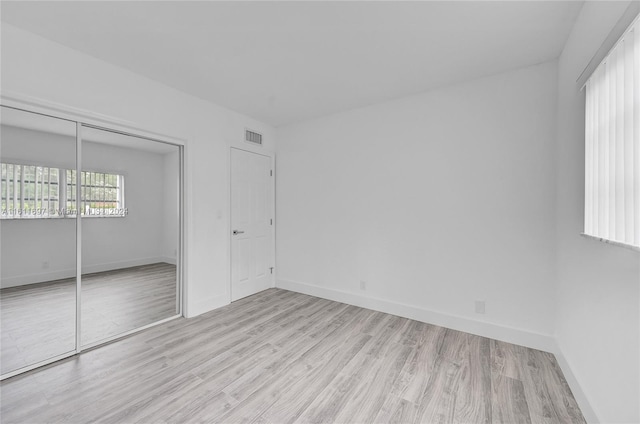 unfurnished bedroom with a closet and light hardwood / wood-style floors