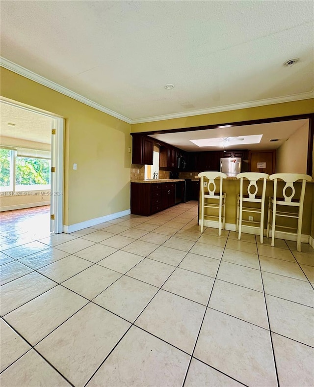 unfurnished living room with crown molding, light tile patterned flooring, a textured ceiling, and a skylight