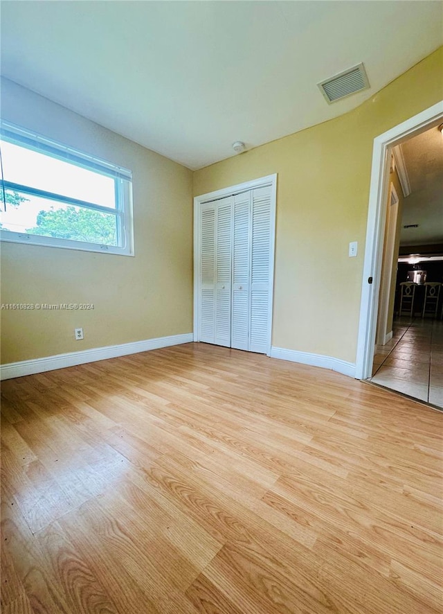 unfurnished bedroom with a closet and light hardwood / wood-style floors