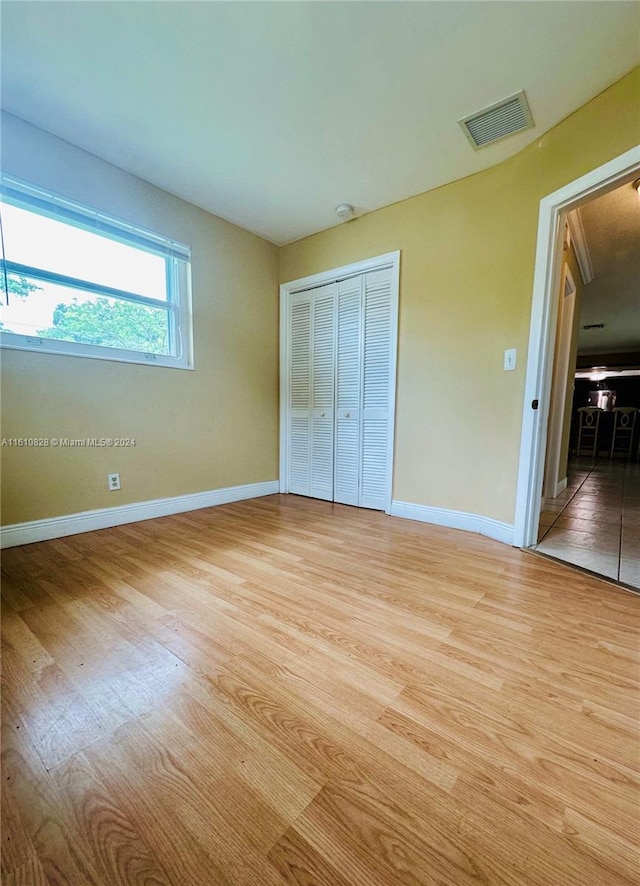 unfurnished bedroom with light hardwood / wood-style flooring and a closet