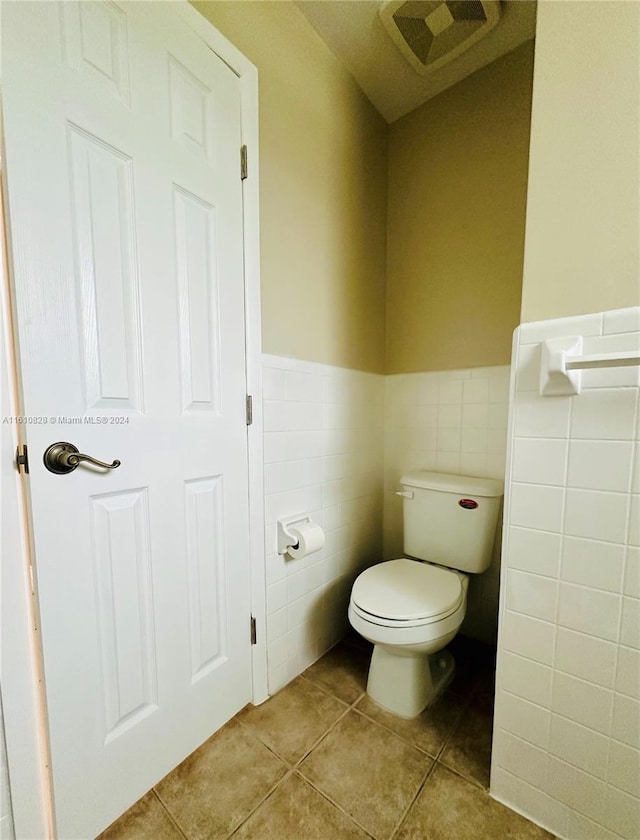 bathroom featuring toilet, tile patterned floors, and tile walls