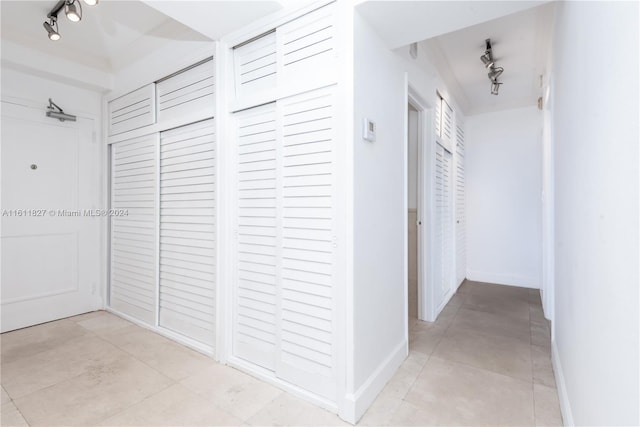 corridor featuring light tile patterned flooring and track lighting