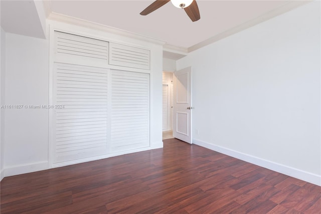 unfurnished bedroom with ornamental molding, dark hardwood / wood-style flooring, ceiling fan, and a closet