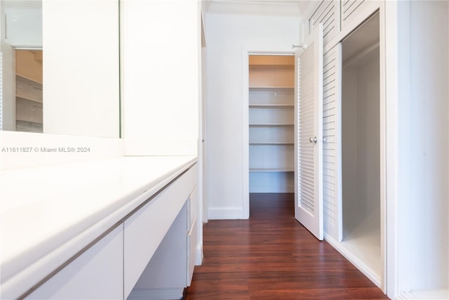 hall with dark wood-type flooring and ornamental molding