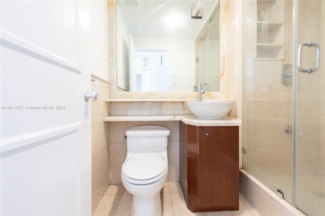 bathroom featuring toilet, vanity, tile patterned flooring, and a shower with door