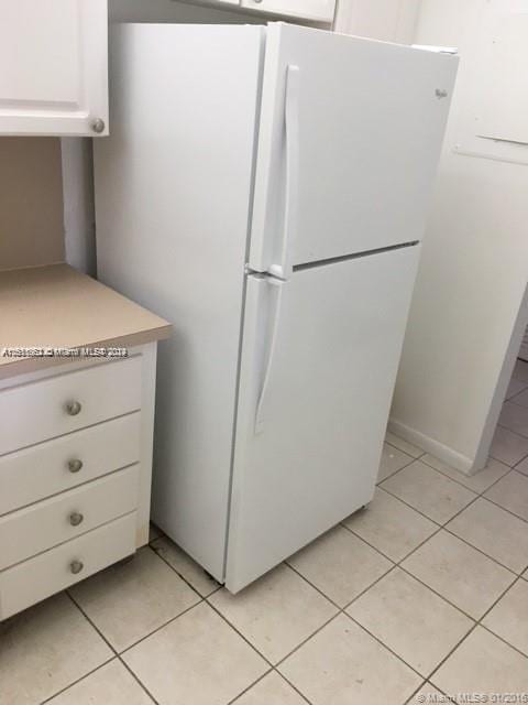 kitchen with white cabinetry, white fridge, and light tile patterned floors