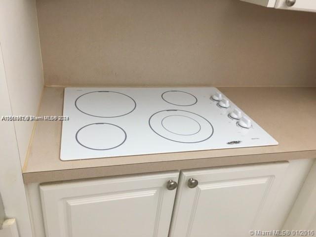 interior details with cooktop and white cabinetry