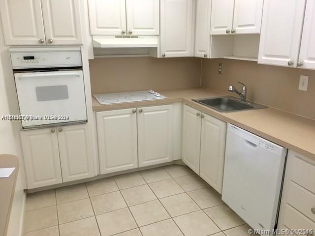 kitchen with sink, white appliances, light tile patterned floors, and white cabinets