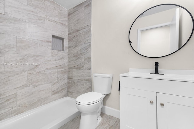 bathroom with tiled shower, vanity, and toilet