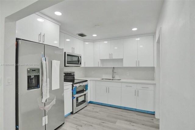 kitchen with sink, white cabinetry, light wood-type flooring, and stainless steel appliances