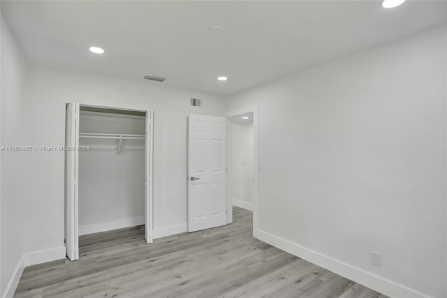 unfurnished bedroom with light hardwood / wood-style flooring and a closet