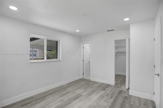 unfurnished bedroom featuring light hardwood / wood-style flooring, a closet, and a walk in closet