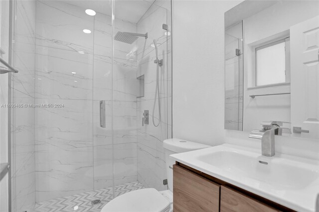 bathroom with a shower with door, vanity, and toilet