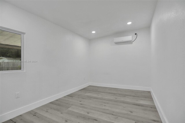 empty room with a wall mounted AC and light hardwood / wood-style floors