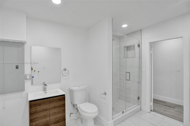 bathroom featuring a shower with door, hardwood / wood-style floors, toilet, electric panel, and vanity