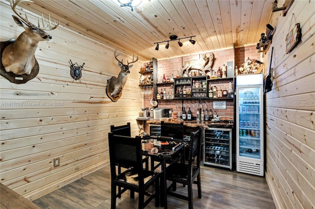 dining area featuring beverage cooler, wood ceiling, wood-type flooring, track lighting, and wood walls