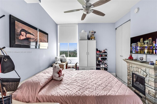 bedroom with ceiling fan, a closet, and a fireplace