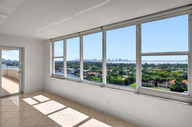 spare room with light tile patterned floors, a view of city, and baseboards