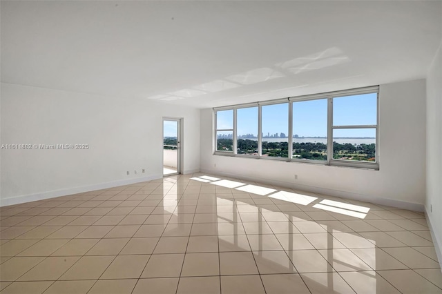 unfurnished room with light tile patterned floors and baseboards