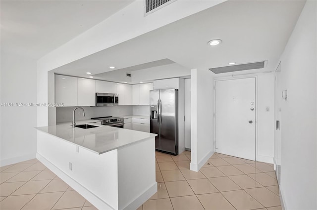 kitchen featuring a sink, stainless steel appliances, a peninsula, light countertops, and light tile patterned floors