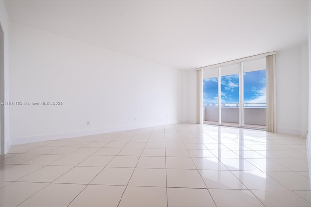 spare room with light tile patterned floors, floor to ceiling windows, and baseboards