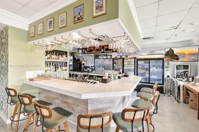 bar with ornamental molding, a paneled ceiling, and light tile patterned floors