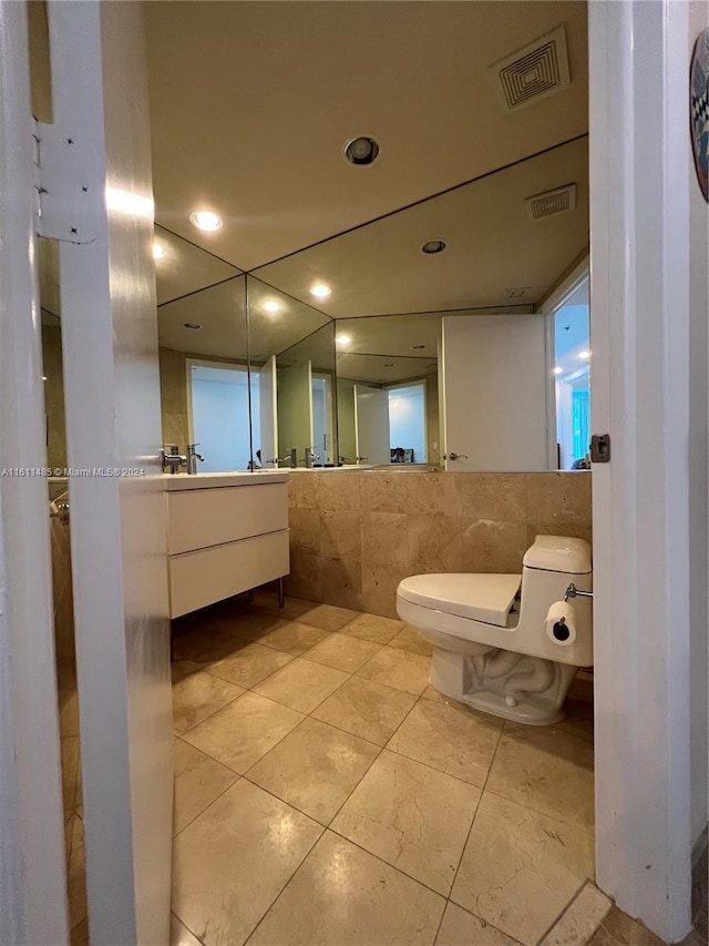 bathroom with vanity, toilet, and tile walls