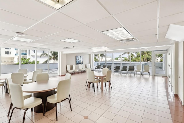 dining area with a paneled ceiling, light tile patterned flooring, and floor to ceiling windows