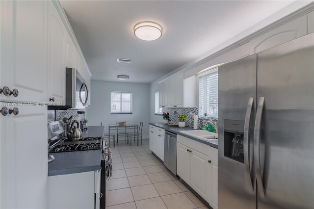 kitchen featuring plenty of natural light, stainless steel appliances, white cabinets, and tasteful backsplash